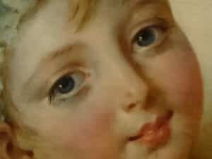 Ein gemaltes Kindergesicht wendet seine blauen Augen dem Betrachter zu. Es macht einen versonnenen Eindruck, der Mund ist geschlossen.